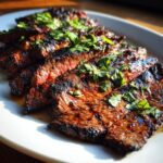 Close-up of perfectly grilled carne asada slices, glistening with marinade and topped with fresh cilantro.
