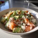 A refreshing cottage cheese smoked salmon salad with chunks of avocado and fresh dill, seasoned with spices.