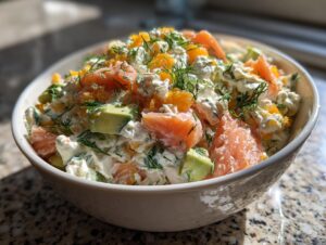 A close-up of a creamy cottage cheese smoked salmon salad with chunks of avocado and fresh dill.
