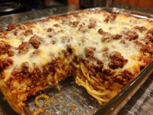 A close-up view of a creamy baked spaghetti casserole topped with melted cheese and meat sauce.