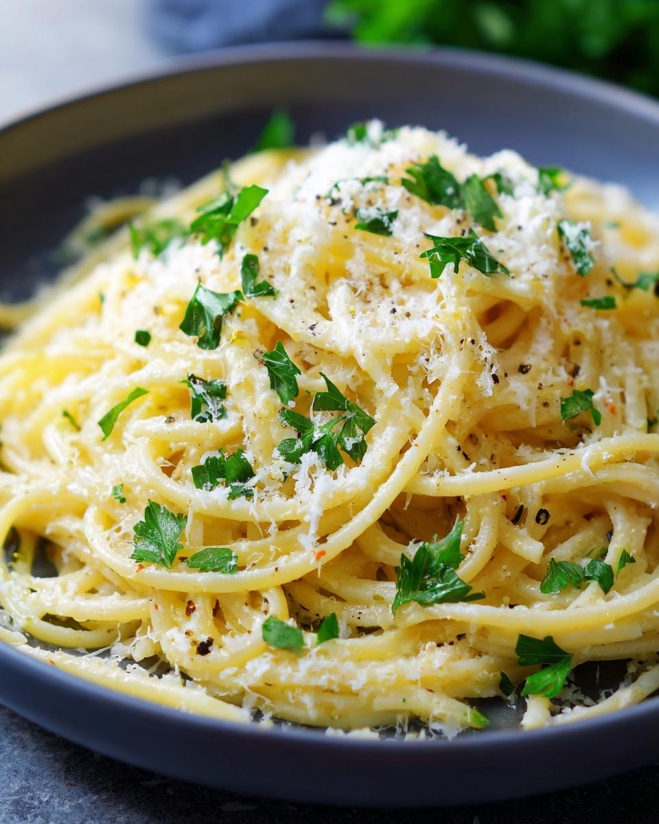 Close-up of a bowl of Creamy Lemon Pasta topped with grated cheese and fresh parsley.
