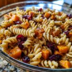 Close-up of a bowl of fall pasta salad with fusilli pasta, diced butternut squash, and dried cranberries.
