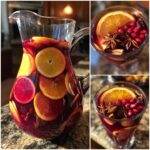 A pitcher and glasses filled with vibrant red Fall Sangria, garnished with orange slices, pomegranate seeds, star anise, and cinnamon sticks.
