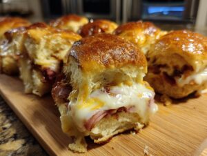 Close-up of delicious ham and cheese sliders with gooey melted cheese and golden brown buns.