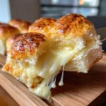 A close-up of a Ham and Cheese Slider being pulled apart, revealing gooey melted cheese.