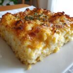 A close-up of a golden-brown slice of hashbrown casserole, topped with herbs.