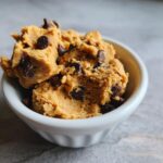 Close-up of a white bowl filled with delicious high protein cookie dough studded with chocolate chips.