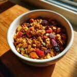 A white bowl filled with delicious homemade granola, featuring oats, nuts, dried fruits, and seeds.