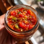 A close-up shot of a jar filled with vibrant, chunky homemade salsa, showing tomatoes and peppers.