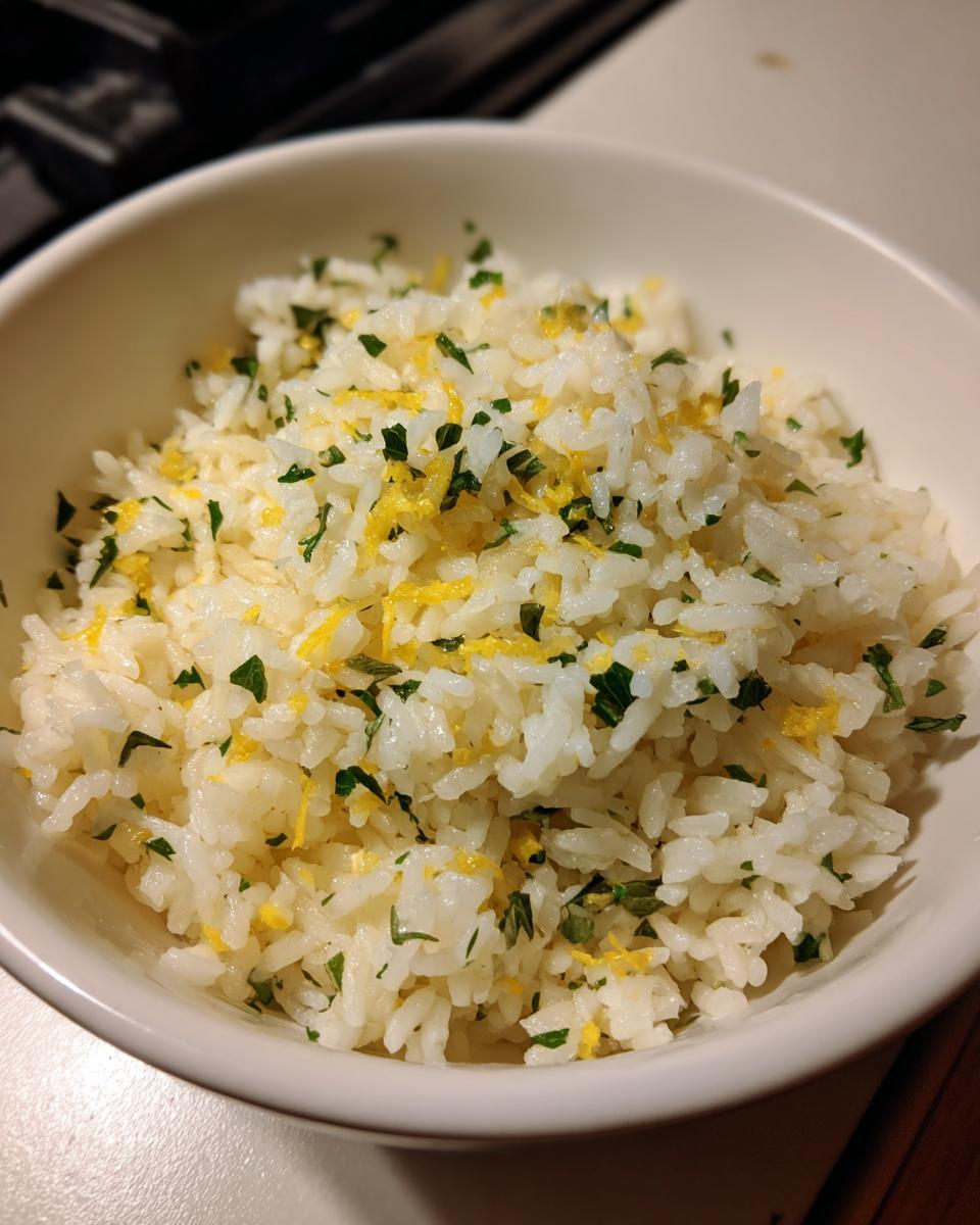 A bowl of fluffy Mediterranean lemon rice topped with fresh parsley and lemon zest.