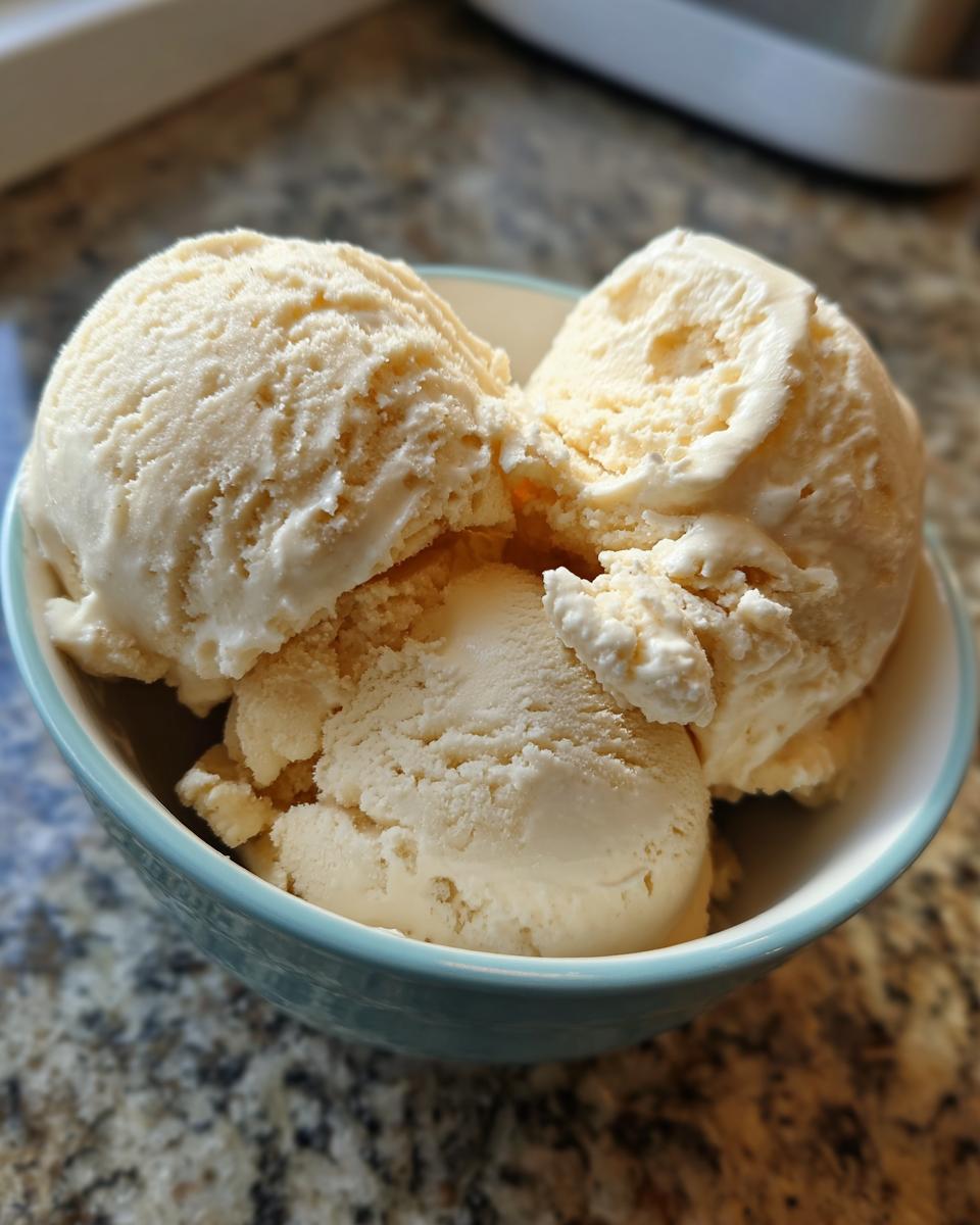 Close-up of three scoops of creamy vanilla protein ice cream in a light blue bowl.