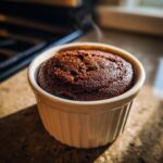 A freshly baked chocolate protein mug cake steaming in a white ramekin.