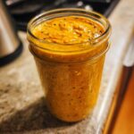 A close-up of a glass jar filled with creamy pumpkin overnight oats and chia seeds.