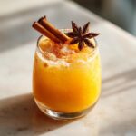 A refreshing Pumpkin Pie Ginger Smash cocktail garnished with cinnamon sticks and star anise.