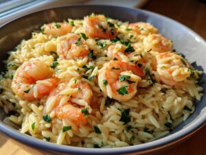 A bowl of shrimp orzo in a creamy lemon garlic sauce, garnished with fresh parsley.