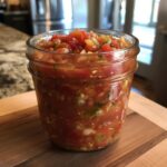 A glass mason jar filled with vibrant, chunky tomato salsa, perfect for a tomato salsa canning recipe.