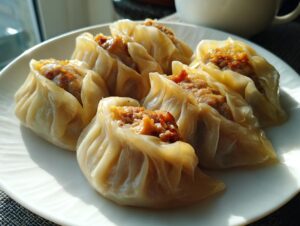 A plate of freshly made Traditional Chinese Dumplings, showcasing their delicate wrappers and savory meat filling.