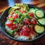 A vibrant Tuna Poke Bowl served over rice, topped with fresh tuna cubes, sliced avocado, cucumber, green onions, and sesame seeds.