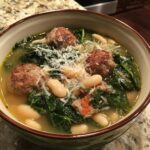 A hearty bowl of Tuscan white bean soup with sausage, kale, and Parmesan cheese.