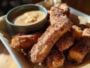Golden brown air fryer apple wedges coated in cinnamon sugar, served with a side of caramel dipping sauce.