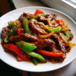 Close-up of savory pepper steak strips mixed with green and red bell peppers and onions.