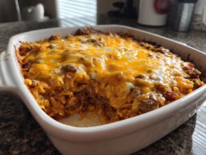 A close-up of a freshly baked Amish country casserole in a white baking dish, topped with melted cheddar cheese.