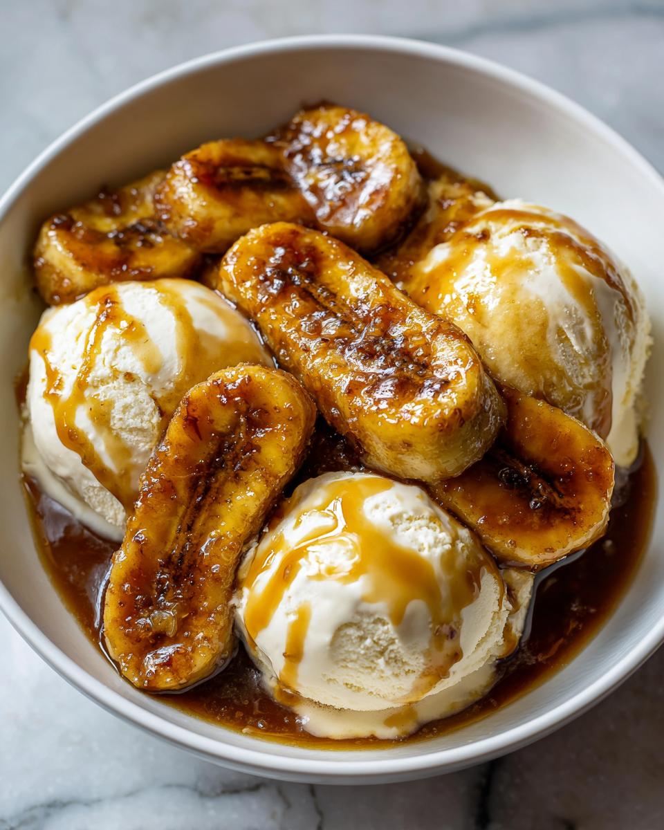 Close-up of caramelized bananas and scoops of vanilla ice cream drenched in caramel sauce, classic Bananas Foster.