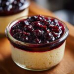 Close-up of a creamy Blueberry Vanilla Bean Panna Cotta topped with a rich blueberry compote in a glass ramekin.