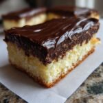 A close-up of a rich Boston Cream Pie Fudge slice with a thick chocolate glaze over a fluffy cake base.