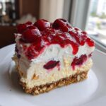 A generous slice of Cherry Pecan Cheesecake Lush, topped with glossy cherries and rich cream.