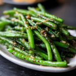 A close-up of vibrant Chinese green beans tossed in a glistening garlic sauce.