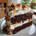 A rich slice of chocolate caramel toffee crunch cake with layers of chocolate cake, whipped cream, and caramel drizzle.