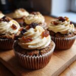 Close-up of festive Christmas pudding cupcakes topped with creamy frosting and raisins.