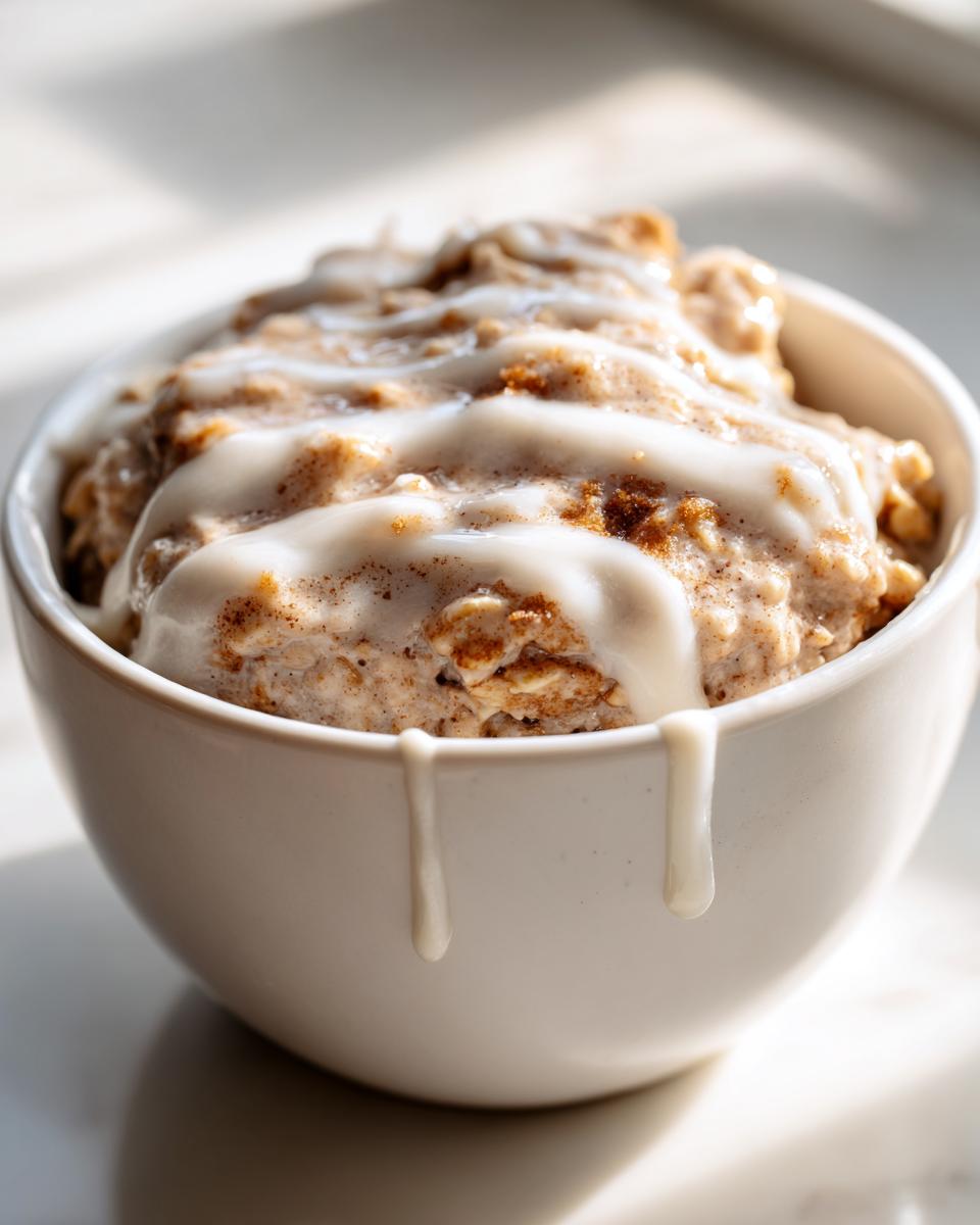 Close-up of creamy overnight oats topped with a thick white icing drizzle, perfect for a high-protein breakfast.
