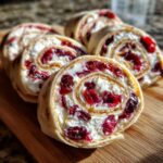 Close-up of delicious cranberry tortilla roll ups filled with cream cheese and cranberries on a wooden board.