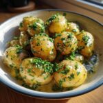 A close-up of a bowl filled with creamy garlic baby potatoes, generously topped with fresh parsley.