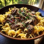 A hearty bowl of Crock Pot Beef Stroganoff served over wide egg noodles, garnished with fresh parsley.