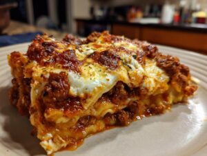 A close-up of a hearty slice of Crockpot ravioli lasagna, featuring layers of pasta, rich meat sauce, and melted cheese.