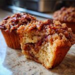 A pecan pie muffin cut in half showing the gooey pecan filling inside the tender cake base.