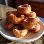A tempting stack of freshly made hot buttered mini donuts, coated in cinnamon sugar.