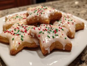 Close-up of star-shaped Italian Christmas cookies topped with white icing and festive red and green sprinkles.