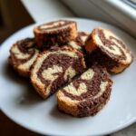 Slices of homemade pinwheel cookies showing a beautiful swirl pattern of vanilla and chocolate dough.