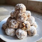 A pile of freshly baked Pecan Snowball Cookies, generously dusted with powdered sugar.
