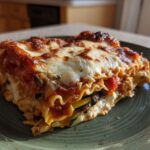 A hearty slice of roasted vegetable lasagna with melted cheese and visible layers of vegetables.