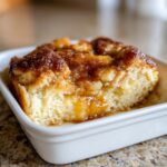 A close-up of a warm slice of snickerdoodle cobbler, featuring a soft cake base and a gooey, cinnamon-sugar topping.