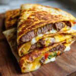 A close-up stack of golden-brown steak and cheese quesadillas, with melted cheese oozing out.