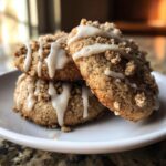 Three stacked coffee cake cookies topped with crumb topping and drizzled with white vanilla glaze.