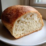 Cross-section of a freshly baked loaf of yeast bread showing a soft, airy interior crumb and golden crust.