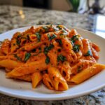 A close-up of creamy tomato basil pasta made with penne noodles, topped with fresh chopped basil.