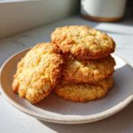 A stack of four golden, textured 3-ingredient butter cookies resting on a speckled ceramic plate.